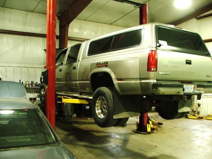 Silver GMC Sierra dually raised on a red two-post lift
